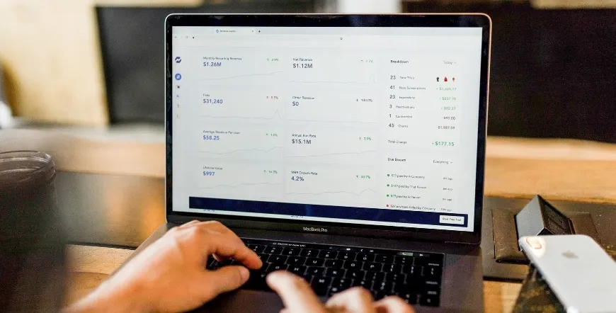 Mâini tastând pe laptop, cu un tabel de date pe ecran